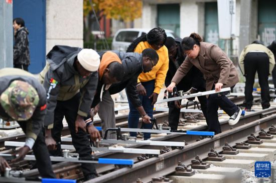 在天津鐵道職業(yè)技術學院，老師指導幾內亞學員使用鐵路軌距尺（11月11日攝）。新華社記者 李然 攝